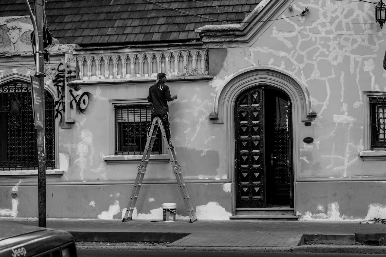 about-img Black and white photo of a man painting a historic building in Mendoza, Argentina.
