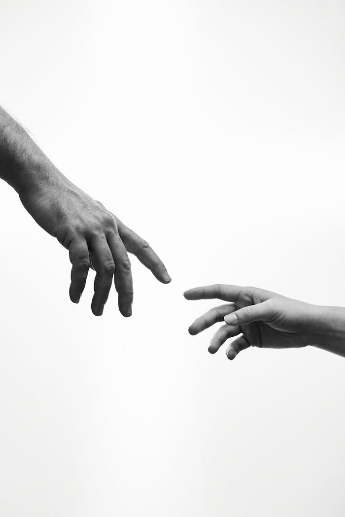 gallery-5 A black and white image of two hands reaching towards each other, symbolizing connection.