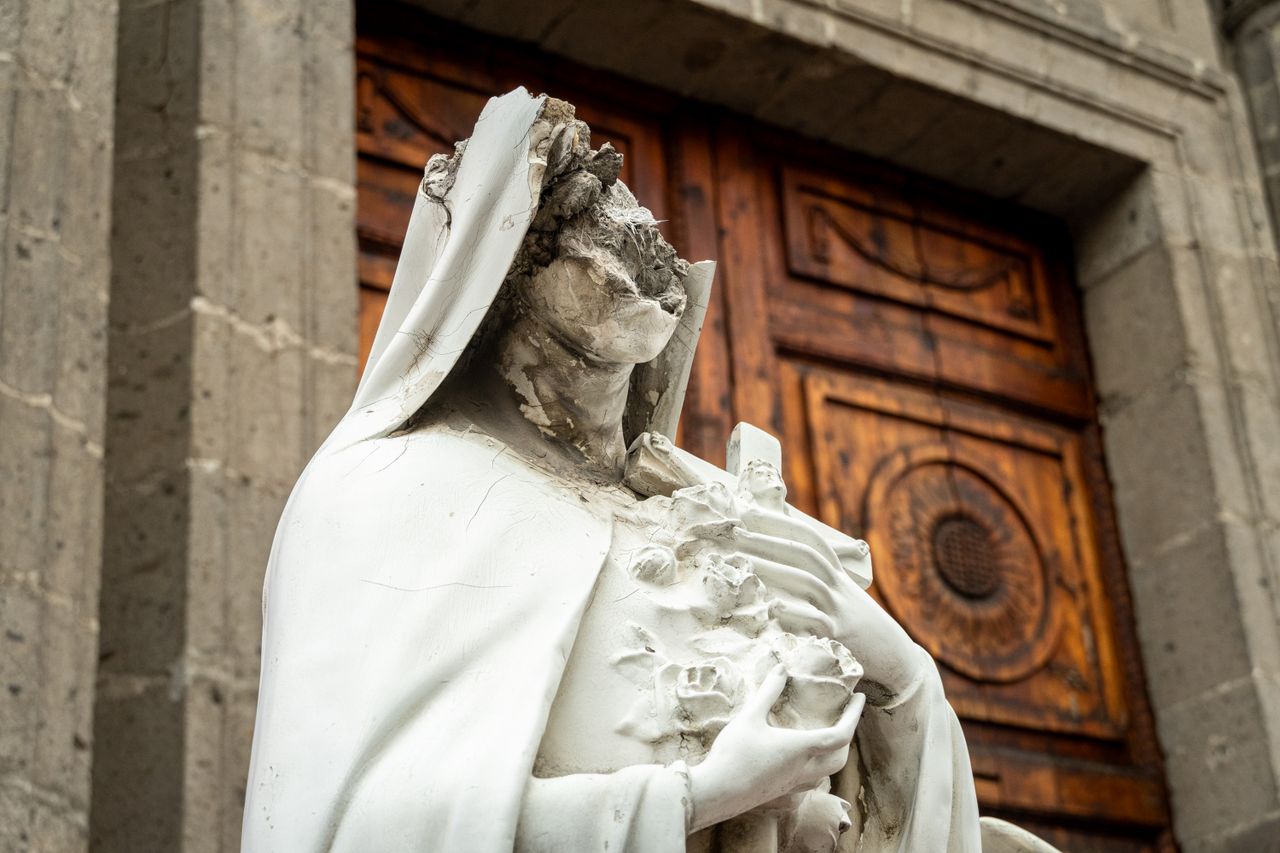 our-experience Damaged white sculpture outside a historical church in Mexico City, showcasing artistic decay.