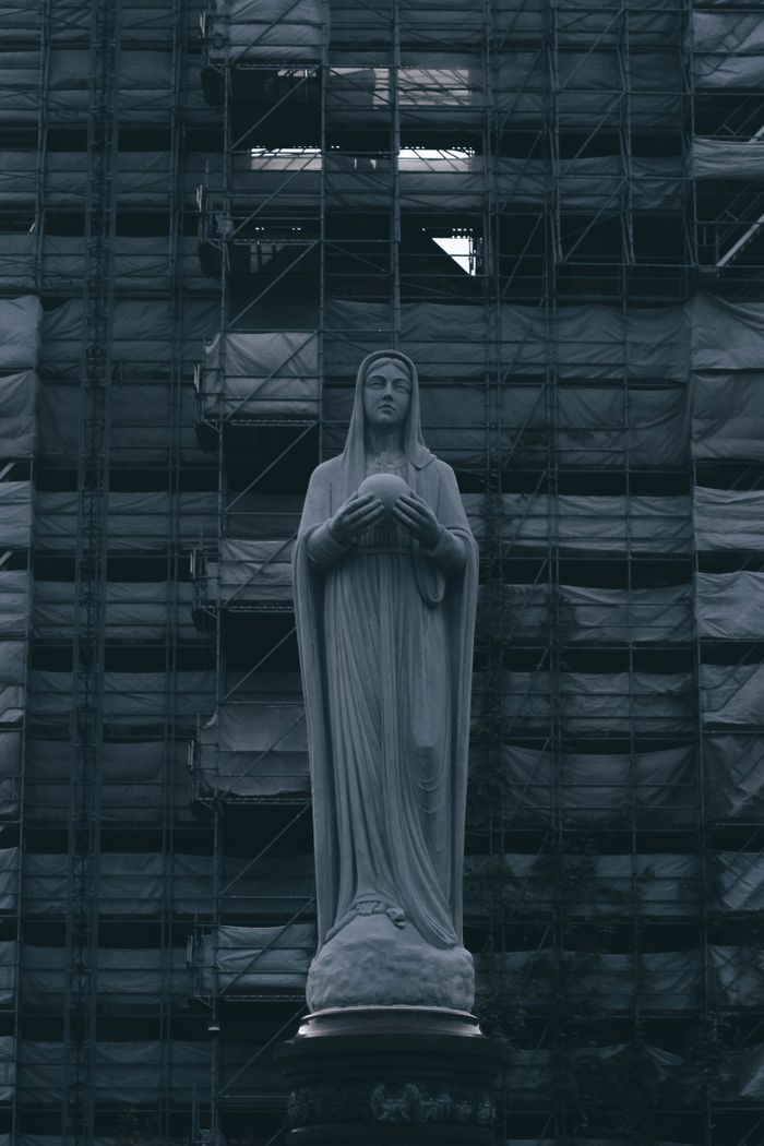services-img Moody photo of Virgin Mary statue against a scaffolded building, mysterious ambiance.