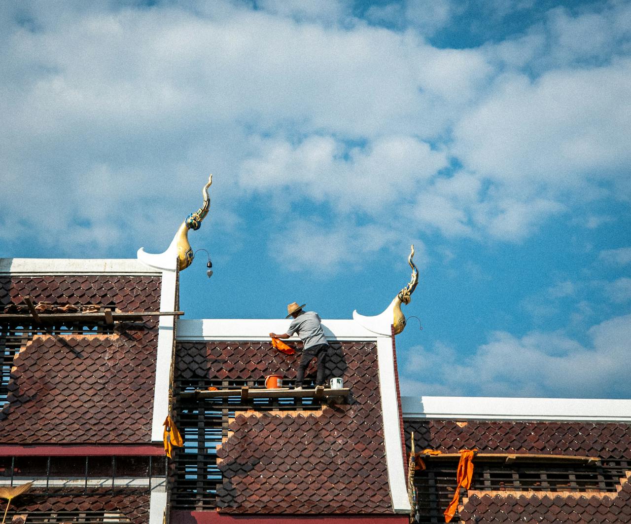 Crafting Captivating Headlines: Your awesome post title goes here A craftsman repairing a temple roof against a vibrant sky in Chiang Mai, Thailand.